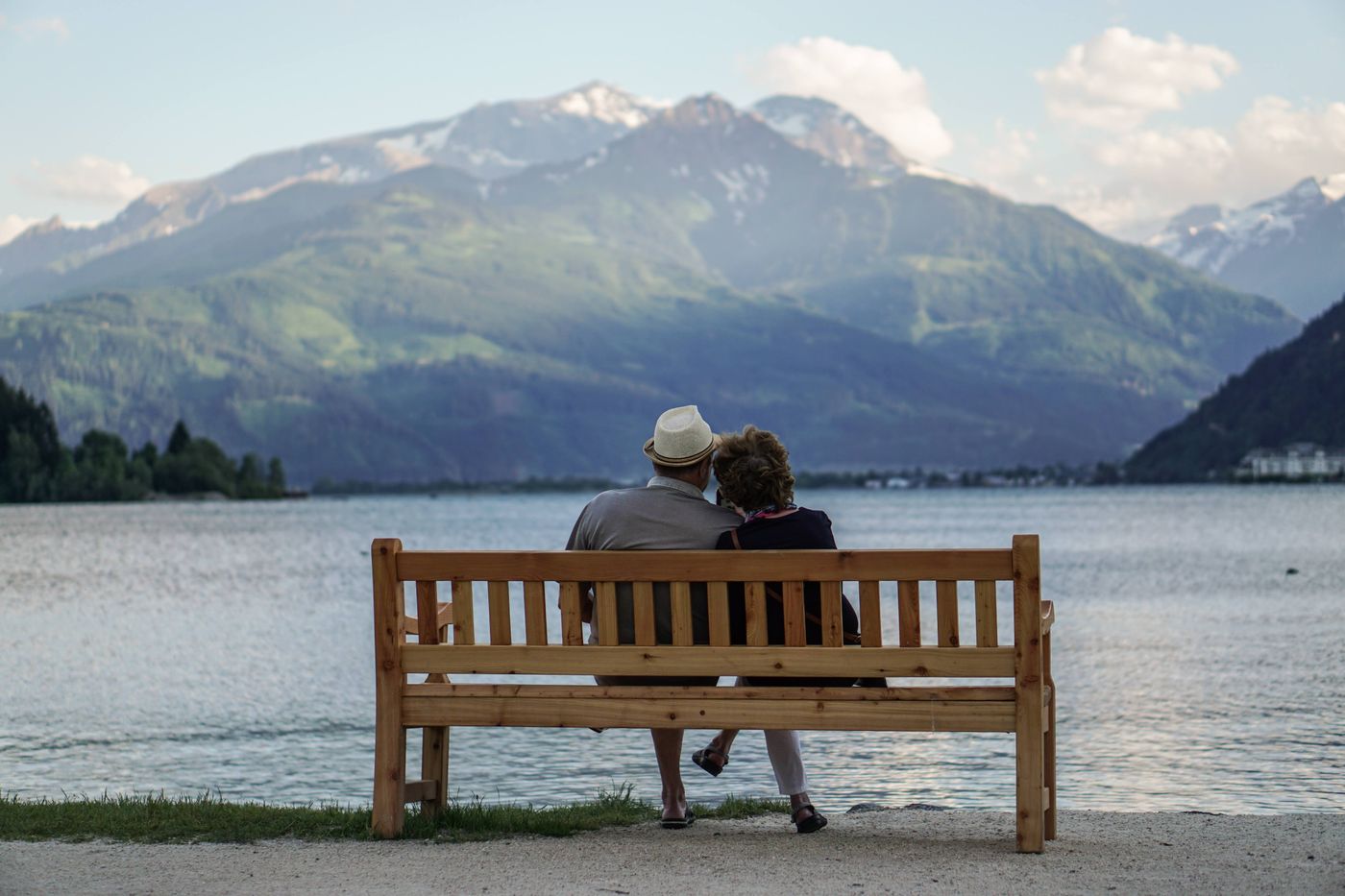 Ein älteres Paar auf einer Bank am See mit Blick auf die Berge in Zell am See