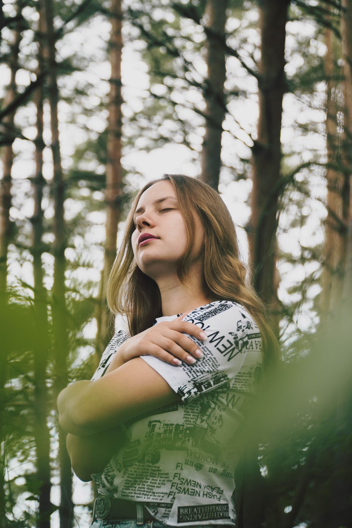 Eine Frau nimmt sich mit geschlossenen Augen einen ruhigen Moment im Wald